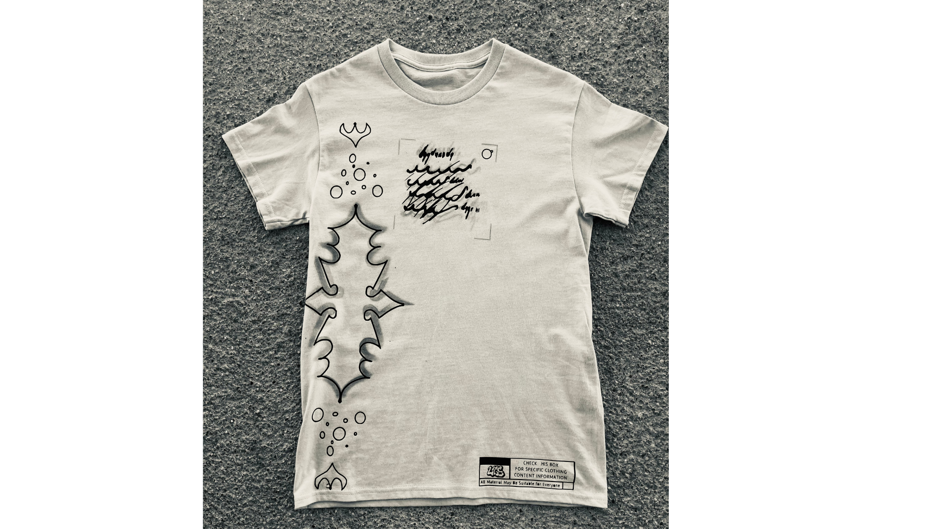 White t-shirt with black graphic design on a textured gray surface